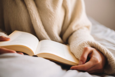 Close up unrecognizable smart girl woman reading book literature in cozy bed bedroom warm sunny lights relaxation comfort read novel hobby relaxing in morning sunny room learning studying at homeの素材