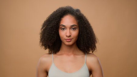 Female portrait in beige studio background attractive African American woman holding fresh avocado near face healthcare cosmetology organic eco cosmetics skin care procedure beautiful girl advertisingの写真素材