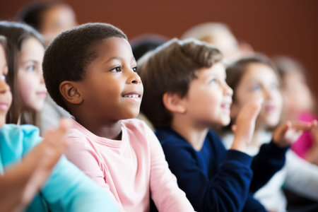 Happy cute african american boy interested schoolchildren smiling interacting elementary pupils in classroom. Kids preschool kindergarten primary school children sitting studying lesson educationの素材
