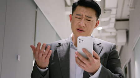 Frustrated upset Asian middle-aged man male chinese korean businessman employer read bad message on...
