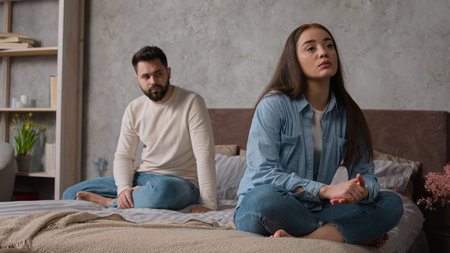 Sad annoyed Caucasian couple family spouses sit apart on bed offended man and woman relationship...