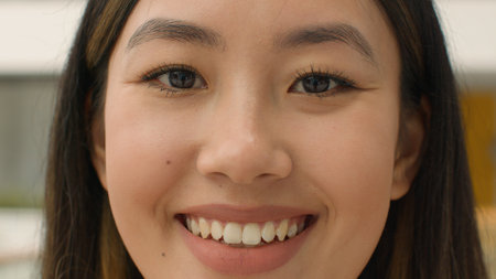 Close up face happy Asian woman smiling chinese korean japanese girl looking at camera head shot joyful lady with natural beauty make-up toothy smile client of cosmetology dental service healthcareの写真素材