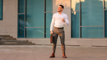 Successful lucky happy arabic spanish business man boss leader candidate entrepreneur with briefcase standing in city near modern building wins achive gets opportunity new job makes victory gestureの写真素材