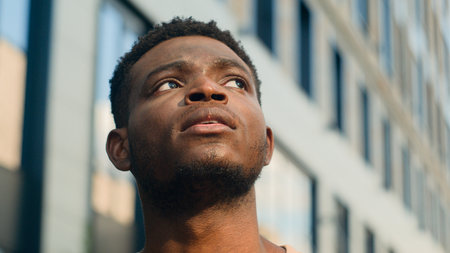 Close up pensive thinking ethnic man looking around outdoor business student guy look up on urban building think thoughtful African American male tourist contemplate outdoors outside lost in cityの写真素材