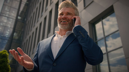 Happy laughing smiling entrepreneur talk cellphone laugh joyful funny discussing speaking calling middle-aged senior business man mature businessman outdoors in city employer talking mobile phone callの写真素材