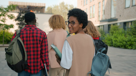 Diverse people group of university friends teens high school pupils multiracial friends classmates students hurry to lesson walking outdoors African American student girl turn around smiling at cameraの写真素材