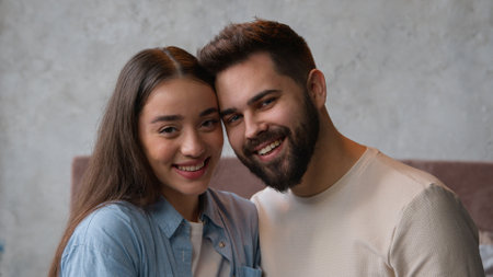 Happy couple in love portrait of Caucasian family married wife and husband newlyweds affectionate cuddling looking at camera tender lovely relationship smiling woman girlfriend and man boyfriend facesの写真素材