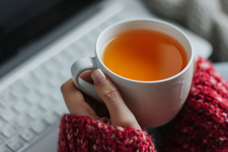 Entrepreneur hands holding aromatic teacup online work from home notebook programmer surfing browsing internet cup of green leaves tea hot steaming beverage morning comfy comfortable drinking warm refreshing drinkの素材