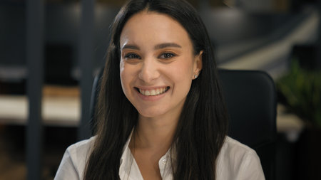 Caucasian businesswoman working in office looking at camera smiling sitting at company corporate...