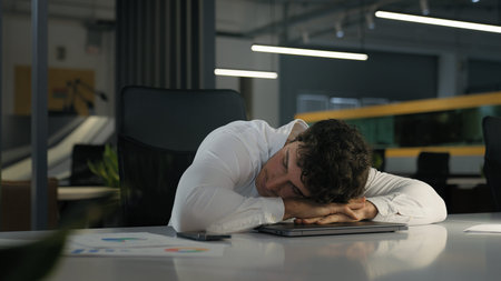 Tired exhausted Caucasian businessman finish work night evening office sleeping relax on computer on table need sleep insomnia disorder fatigued male overworked overtime working business man deadlineの写真素材