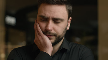 Unhealthy sick Caucasian guy businessman man has toothache oral illness problem with hygiene teeth caries feel dental ache discomfort suffer aching toothy pain sensitive tooth touching inflamed cheekの写真素材