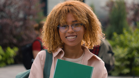 Gen z happy African American smiling student girl holding book textbook glad woman female schoolgirl...