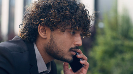 Close up worried Indian businessman stressful Arabian business employer man entrepreneur Hispanic manager talking mobile phone answer call bad news hearing listening problem headache stress in cityの写真素材