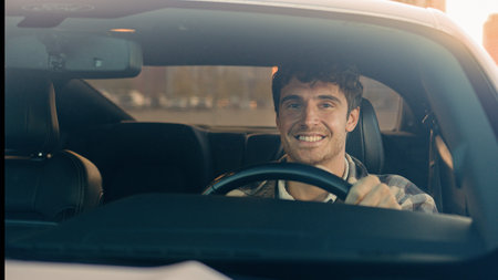 Caucasian handsome smiling man businessman sit inside modern electric car driving automobile in city...