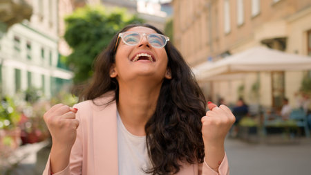 Laughing joke toothy smiling cheerful happy woman Indian Arabian female girl lady outside street town. Joyful hope businesswoman enjoy celebrating victory success achievement win surprise good newsの写真素材