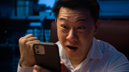 Happy smiling excited winner Asian man victory with phone win shout screaming with winning mobile...
