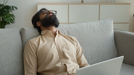 Tired exhausted freelancer working with laptop at home overworked Arabian muslim man fall asleep on...