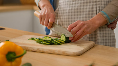 Family two Caucasian couple at kitchen wife woman cook vegetable salad cut fresh cucumber husband...