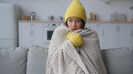 Frozen Asian Chinese Korean woman sick sad girl freezing sit in cold apartment suffer low...