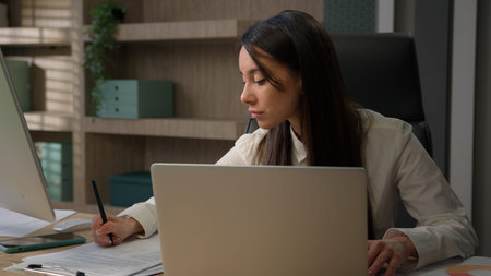 Caucasian business woman multitasking busy in office working online with laptop talking mobile phone...