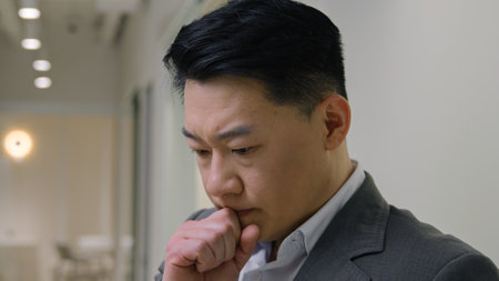 upset thoughtful chinese korean middle-aged businessman texting messages online business social networking receive bad news lost think with smartphoneの写真素材