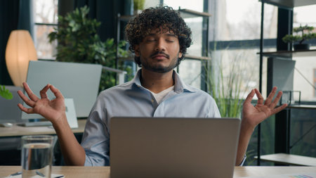 Calm Arabian latin man Indian businessman meditate at office desk zen meditation relaxed male business CEO employer control emotion reduce stress relief harmony balance peace relax computer work pauseの写真素材