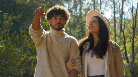 Carefree married multiethnic couple Hispanic woman girl African American man boy walking point finger hold hands. Female wife male husband smile talking relaxing on a date sunshine in park family bondの写真素材