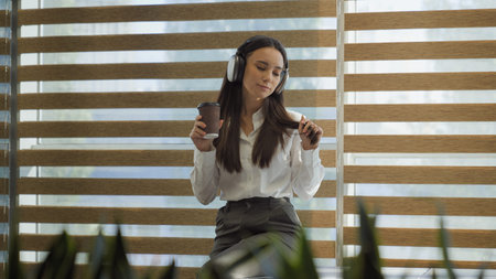 Caucasian relaxed happy dancing businesswoman girl in office work pause break listening music song...