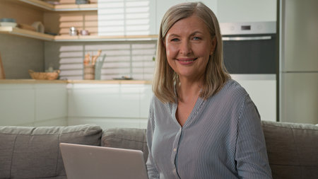 Smiling satisfied senior old Caucasian woman elderly retired female grandmother holding credit card...