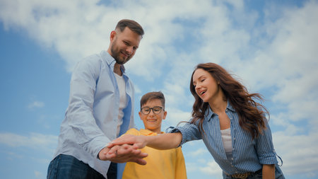 Low angle happy friendly Caucasian family parents mother father little boy son kid child hands stack team celebrate teamwork gesture enjoying together outside nature friendship unity childcare supportの写真素材