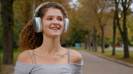 Smiling woman carefree girl positive happy Caucasian female runner listen song in earphones running...