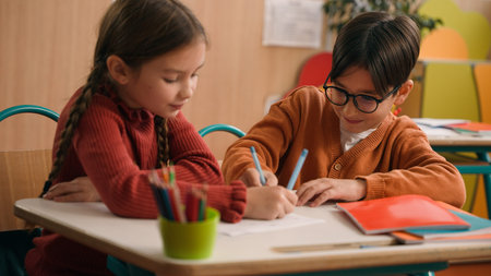 School education studying two funny playing Caucasian little girl daughter child kids children writing in classroom play game drawing fun competition class lesson boy son guy classmates friends writeの写真素材