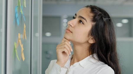 Concentrated pensive young woman manager project leader thinks develops strategy explores...