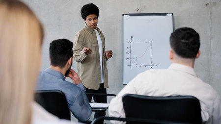 Young male manager presenting project plan to colleagues in meeting explaining report schedule ideas...