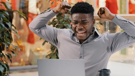 Close-up young excited businessman reads good news by email on laptop amazed happy guy winner celebrates victory celebrating success feels joy winning game online in computer application for gamblingの写真素材