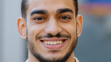 Close up outdoors head male portrait young hispanic happy smiling handsome business man standing in city. Healthy bearded guy arabic client with healthy white toothy dental smile looking at cameraの写真素材