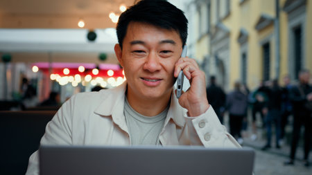 Man talking on phone looking at laptop screen male tourist client making order in online store remotely booking ticket on Internet businessman freelancer discussing business issues using telephoneの写真素材
