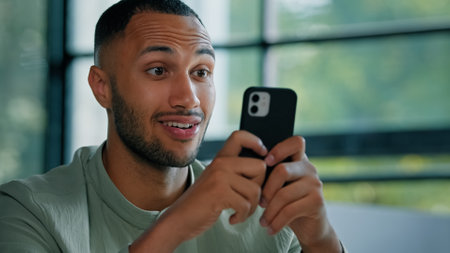Close up male man African businessman guy entrepreneur looking mobile phone reading news email message offer goal achievement amazed wonder shocked surprised expression shock surprise amaze online winの写真素材
