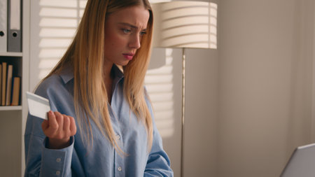 Confused puzzled client female hold bank credit card try to pay online annoyed with payment rejection problem wrong password. Worried girl woman trouble virtual money unsuccessful shopping with laptopの写真素材