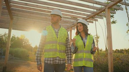 Two successful Caucasian workers man male guy female woman girl builders walking stroll under...