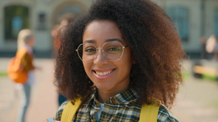 Happy positive toothy smiling African American student girl female woman lady in glasses standing in...
