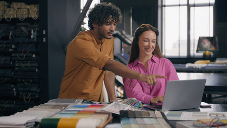 Multiracial business coworkers male female fashion designers work laptop discuss design project in...