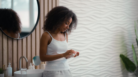 Healthy African American beautiful woman sick ill girl female taking pill with glass of water drinking remedy vitamins supplements at morning bathroom daily medication for beauty skin hair careの写真素材