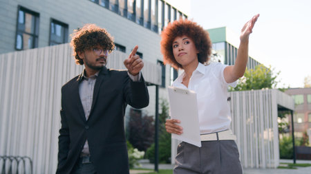 African American woman businesswoman showing building commercial property city skyscrapers company office urban to male client buyer investor walking Indian man Arabian businessman business discussの写真素材