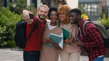 Multiracial students multiethnic friends African American women Caucasian men pupils university college campus outdoors talking after lesson studying make selfie photo with mobile phone shooting videoの写真素材