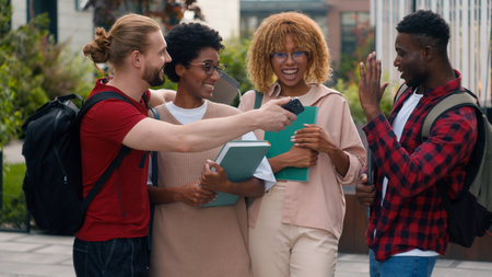University friendship funny speaking emotional joyful diverse people teens high school pupils happy multiracial friends classmates multiethnic students smiling talking laughing walking city outdoorsの写真素材