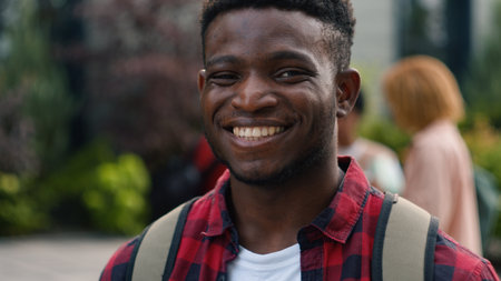 African American young student man guy smiling happy carefree pupil high school schoolboy smile at camera standing on background of talking diverse multiracial students friends education outdoorsの写真素材
