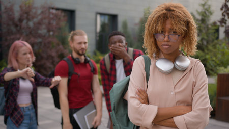 Group of multiracial students friends classmates bully African American student woman education problem bullied sad upset victim girl mockery school bullying university college cruel teens aggressionの写真素材