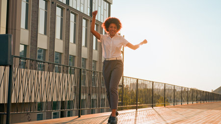 Female silhouette in sunshine city urban active playful happy girl African American business woman walking dancing moving to music rotate celebrate achievement success businesswoman dance go outdoorsの写真素材