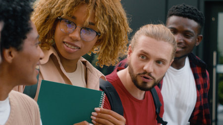 Closeup speaking smiling laughing five gen z diverse multiracial students boys girls talk walk outdoors multiethnic friends happy talking conversation communicate walking college university friendshipの写真素材